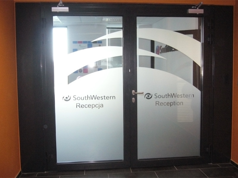 Wylepianie szyb w biurowcu grafiką wyciętą z folii polimerowej samoprzylepnej imitującej piaskowanie szkła, tj. mrożonego szkła w kolorze srebrnym